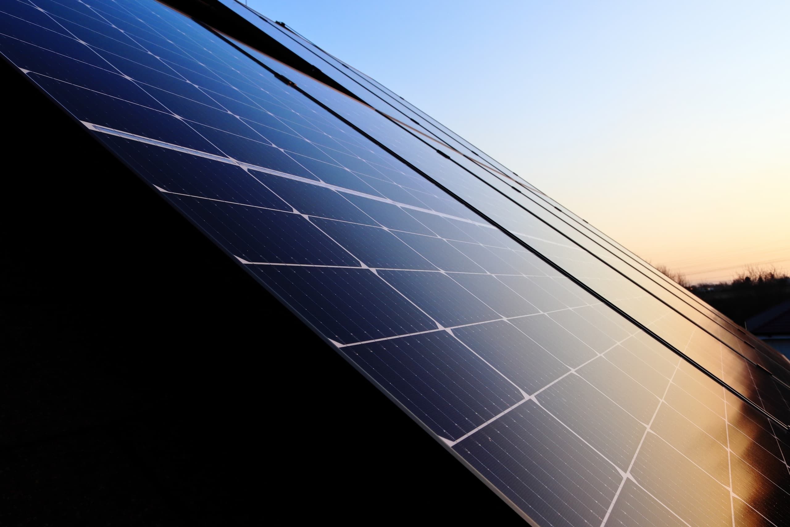 Nahaufnahme von Photovoltaik-Modulen auf einem Hausdach im warmen Licht der Abendsonne.